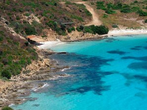 A coastal landscape with a rocky shoreline, a sandy beach, and a clear blue sea. - Ariadimari Hotel (Valledoria)