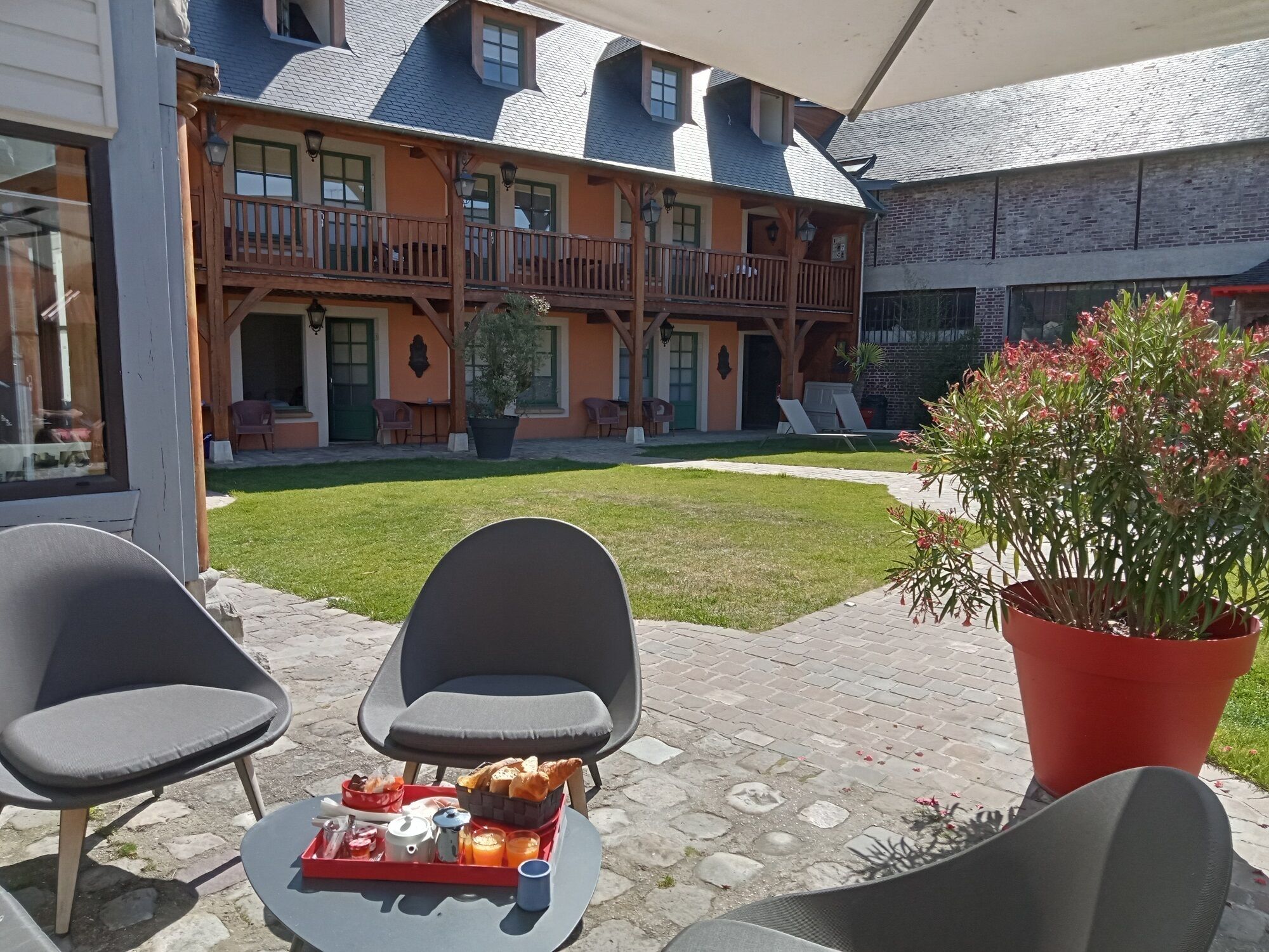 Un patio con dos sillas, una mesa con cosas para el desayuno y una planta en maceta.