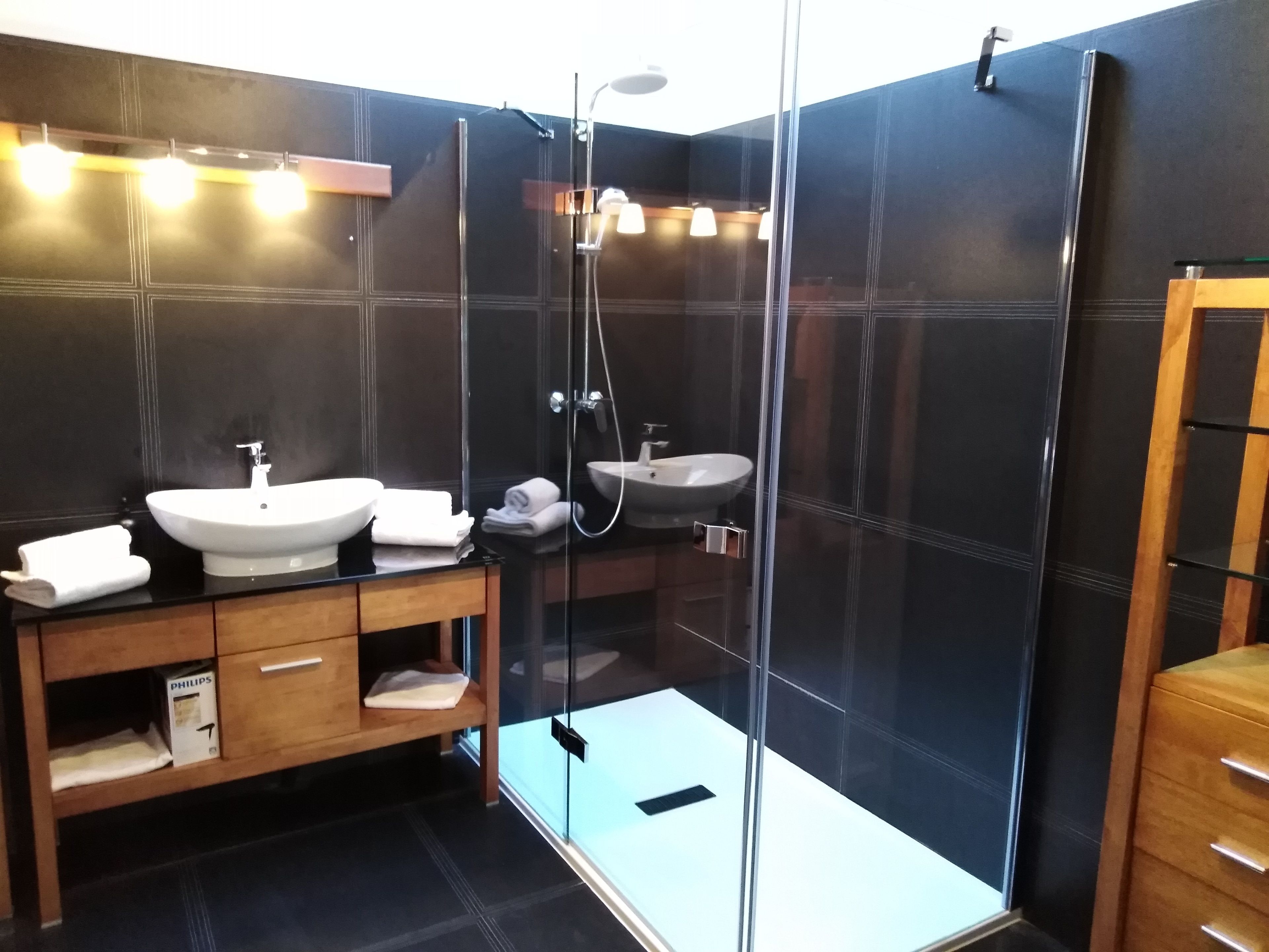 Une salle de bain moderne avec deux vasques, une douche en verre et un meuble-lavabo en bois.