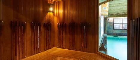 Una sauna con bancos de madera y vista a una piscina al aire libre.