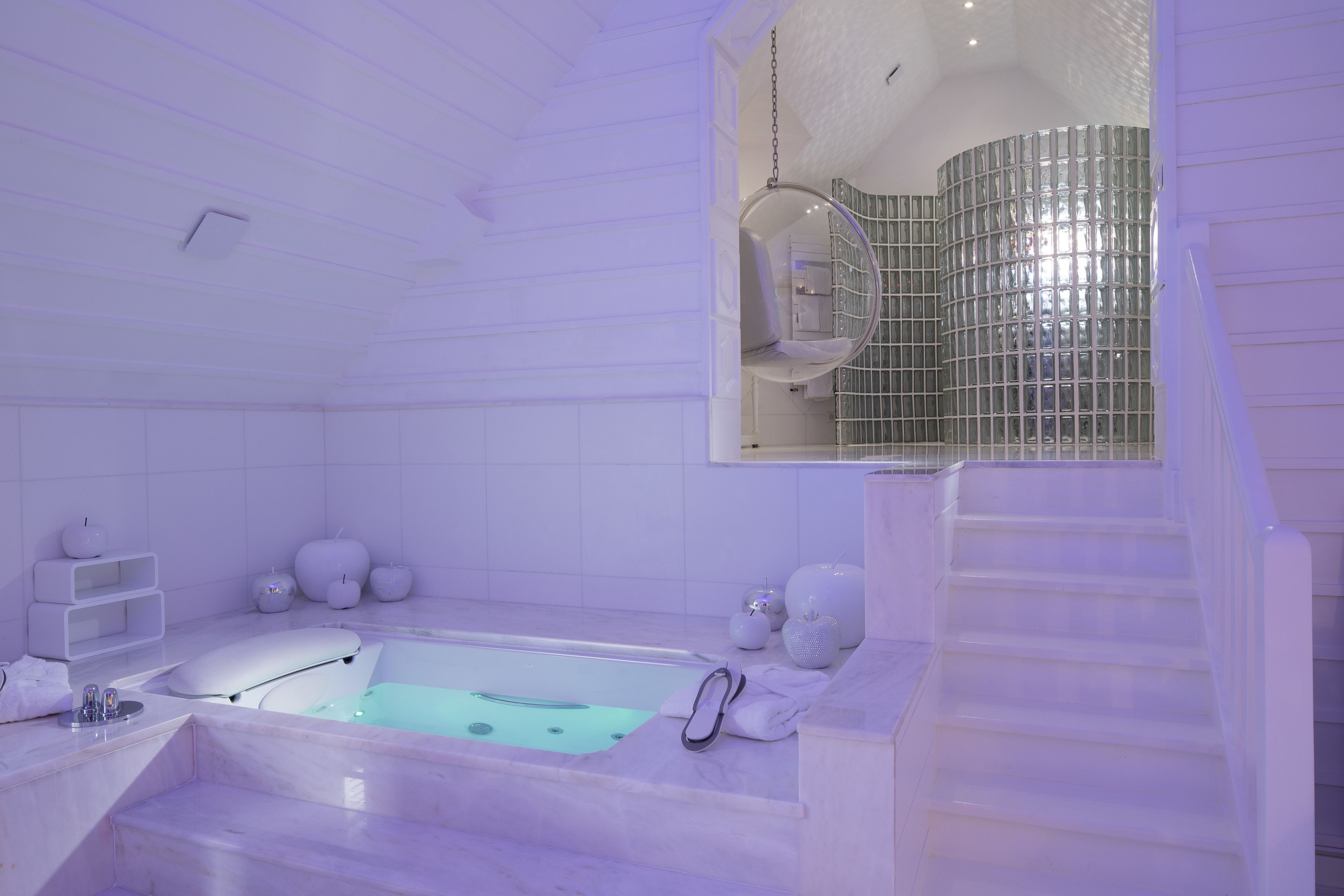 Un baño moderno con una bañera grande, ducha con cerramiento de vidrio y suelo de mármol.