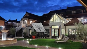 A courtyard with a fountain, outdoor seating, and a large umbrella. - Hôtel et Spa Le Lion d'Or (Pont-l'Eveque)