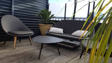 A modern outdoor seating area with a sofa, two chairs, and a small table.