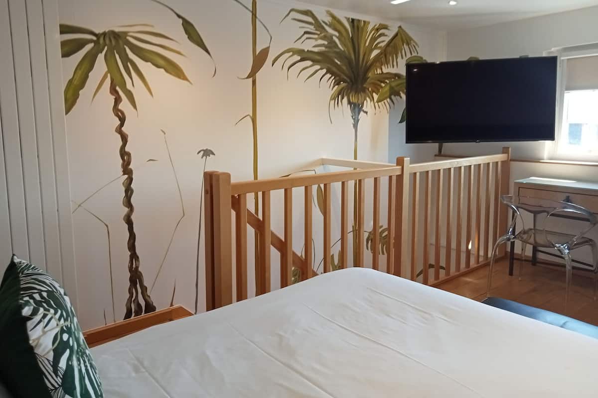 A bedroom with a bed, a TV, a desk, and a chair.