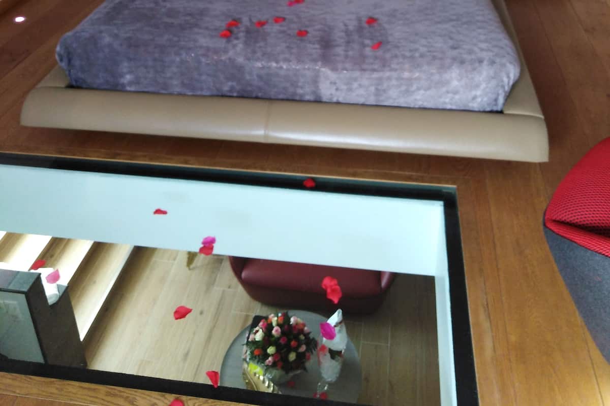 A bedroom with a large bed, a nightstand, a bedside table, and a mirror.