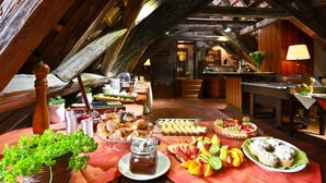 A breakfast buffet with various pastries, fruits, and a honey jar in a rustic room with exposed wooden beams. - Appia Hotel Residences (Prague)