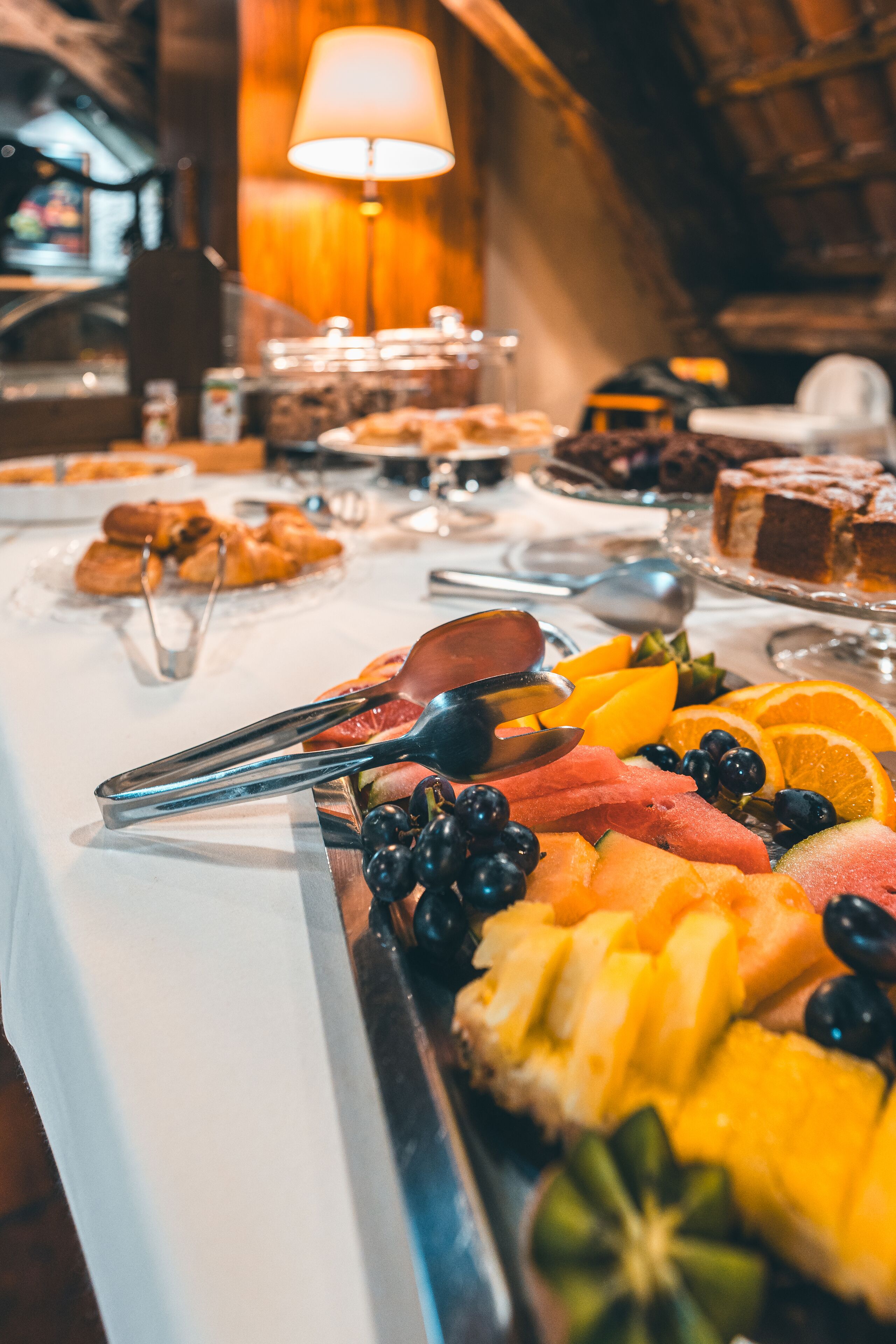 A buffet with various fruits and pastries.