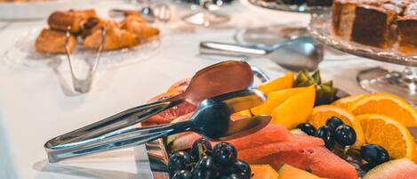 A buffet with various fruits and pastries.