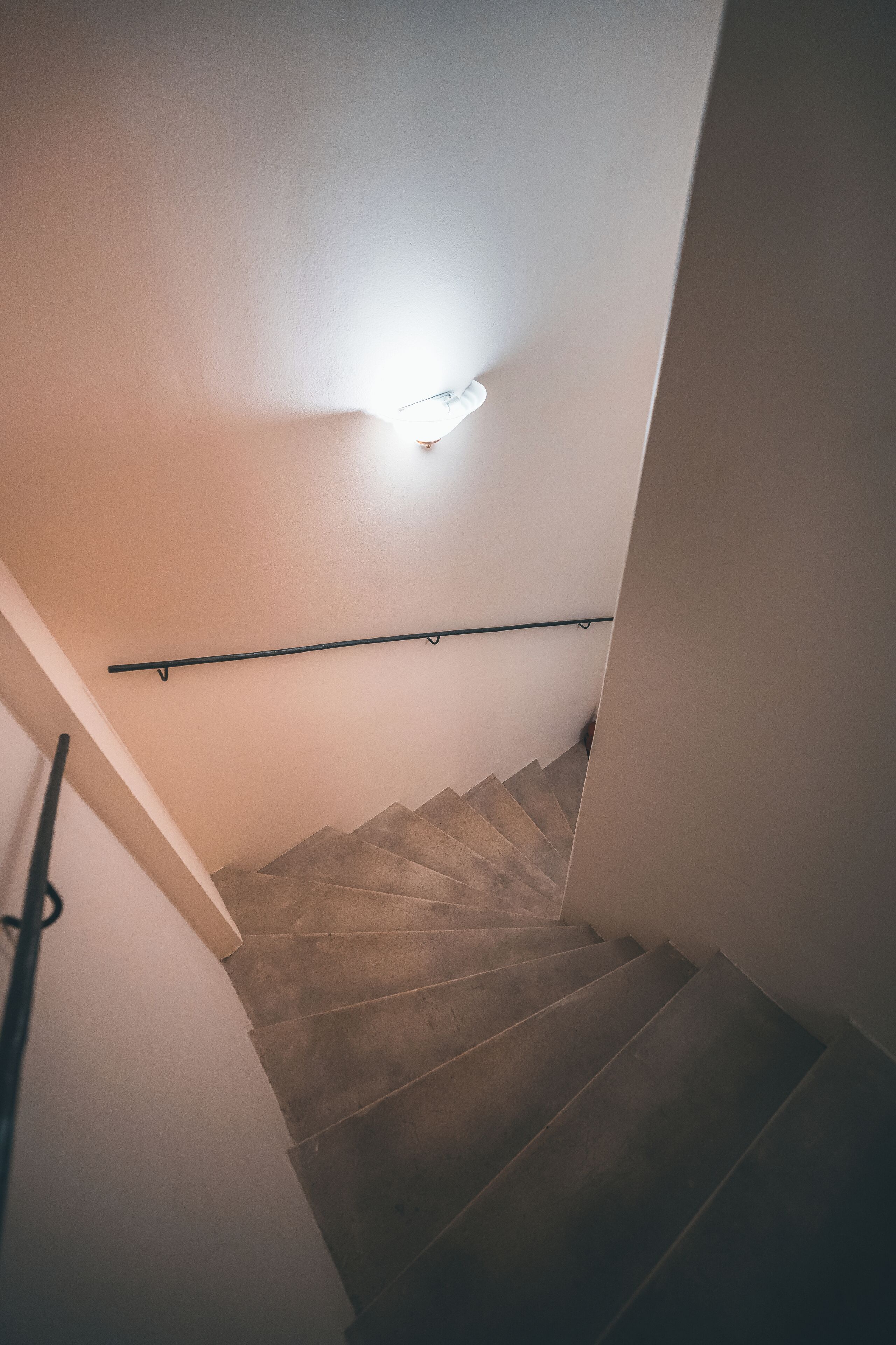 Una escalera con barandilla, un accesorio de luz en la pared y suelo alfombrado.