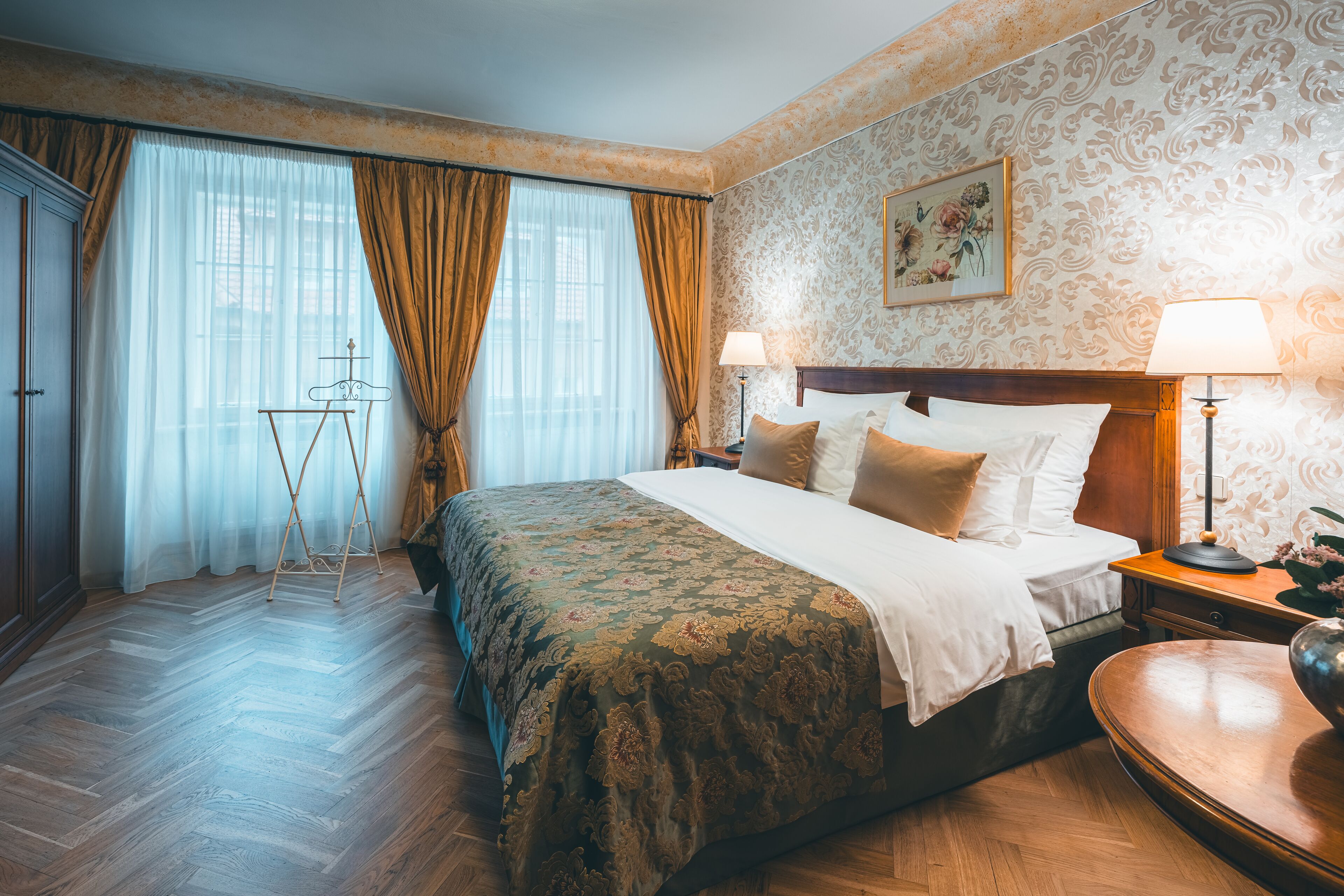 Habitación de hotel con una cama grande, dos lámparas de noche, suelo de madera y un cuadro en la pared.