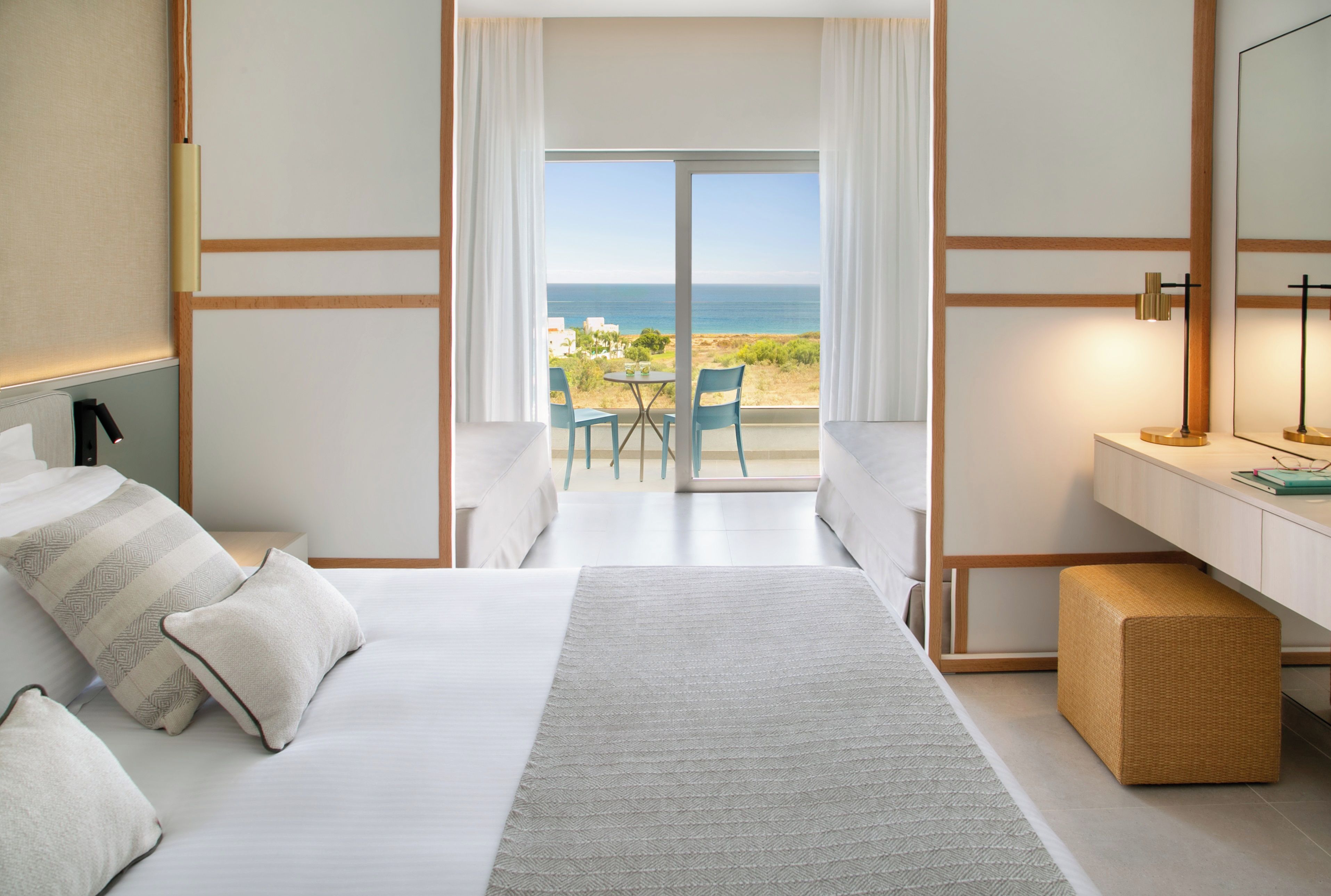 Une chambre d’hôtel avec un lit, un bureau, une chaise et une vue sur la mer.