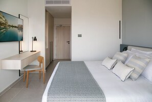 A modern hotel room with a bed, a desk, a chair, and a painting on the wall. - Atlantica Aqua Blue (Paralimni)