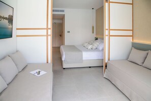 A modern hotel room with a bed, two sofas, a painting, and a door leading to another room. - Atlantica Aqua Blue (Paralimni)