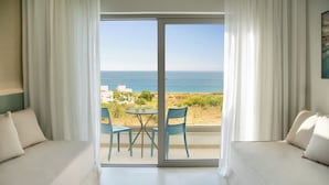 A room with a sofa, a table with chairs, and a view of the sea. - Atlantica Aqua Blue (Paralimni)