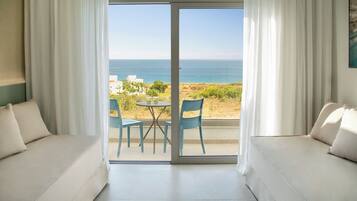 Una habitación con sofá, una mesa y sillas, y vista al mar.