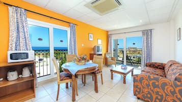 A bright living room with a balcony, a dining table, and a sofa.