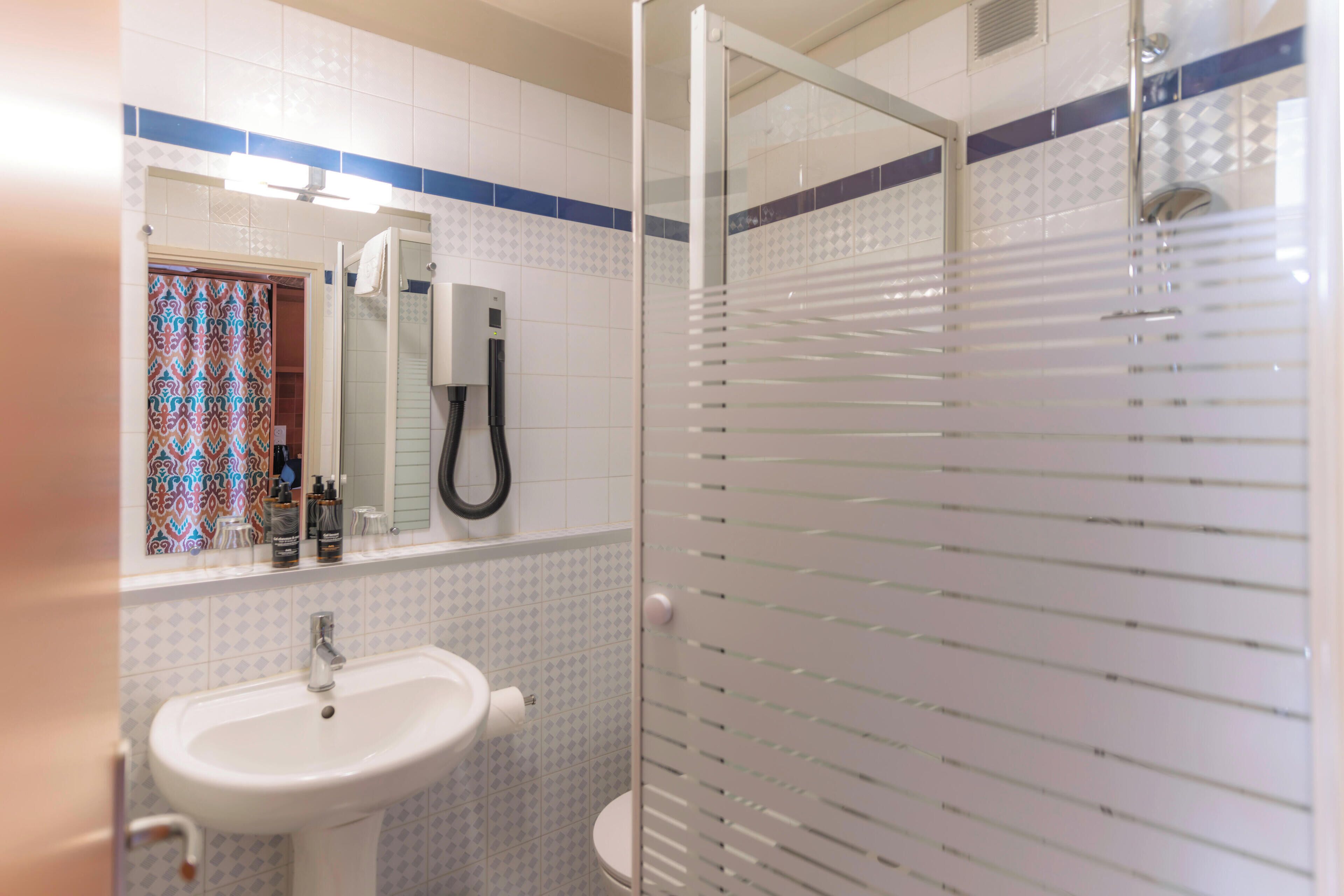 Ein Badezimmer mit Duschkabine aus Glas, Waschbecken und Toilette.