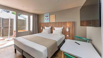 Une chambre d’hôtel avec un lit, une petite table, une chaise, une fenêtre et une porte.