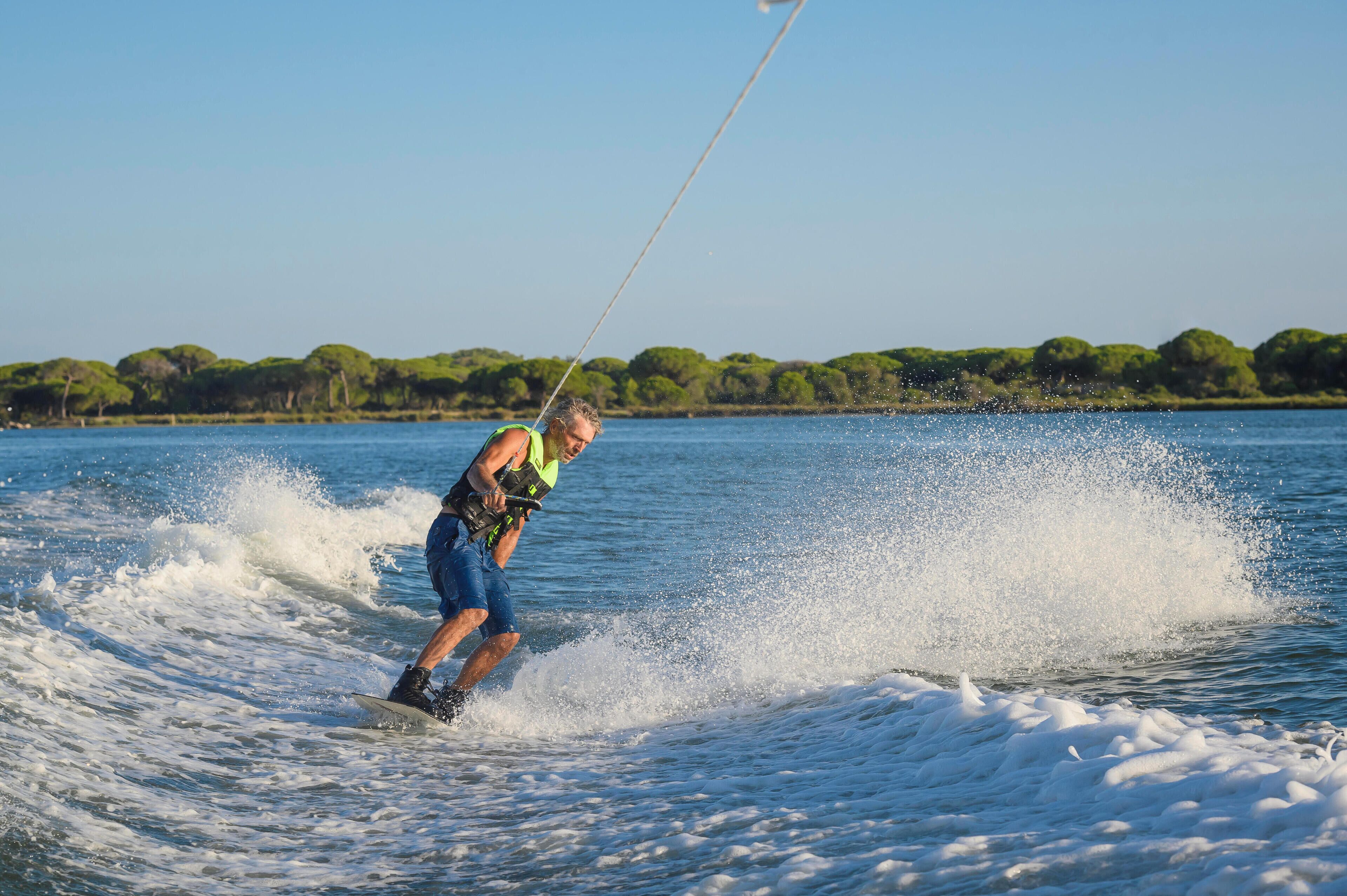 A person wakeboarding on a lake with trees in the background.