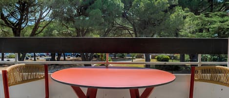 An outdoor seating area with a round table and two chairs, overlooking a forested area.