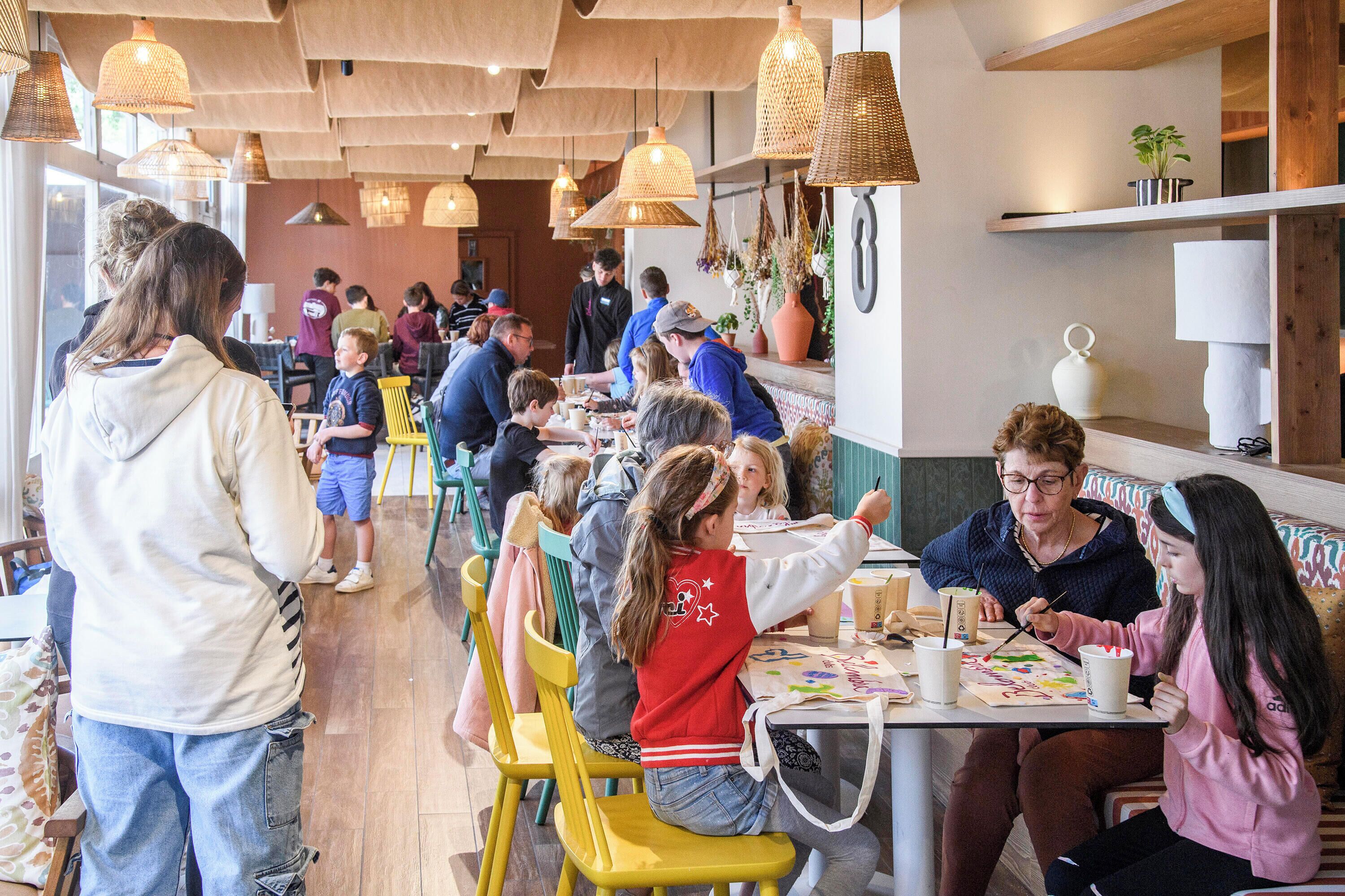 Un comedor con techo de madera, lámparas de mimbre colgantes y diversos arreglos de asientos que incluyen sillas y mesas.
