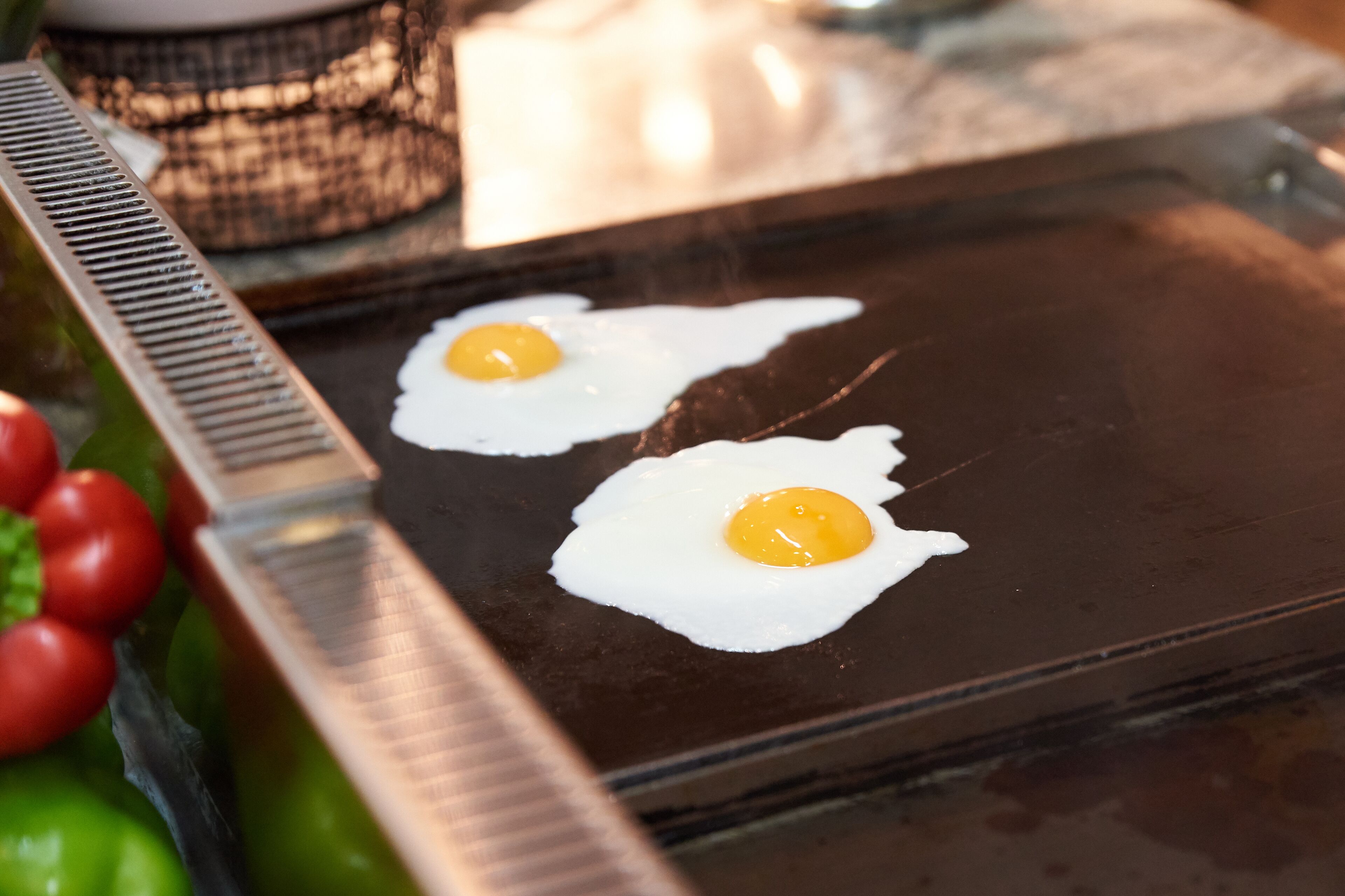 Two sunny-side-up eggs on a hot griddle.