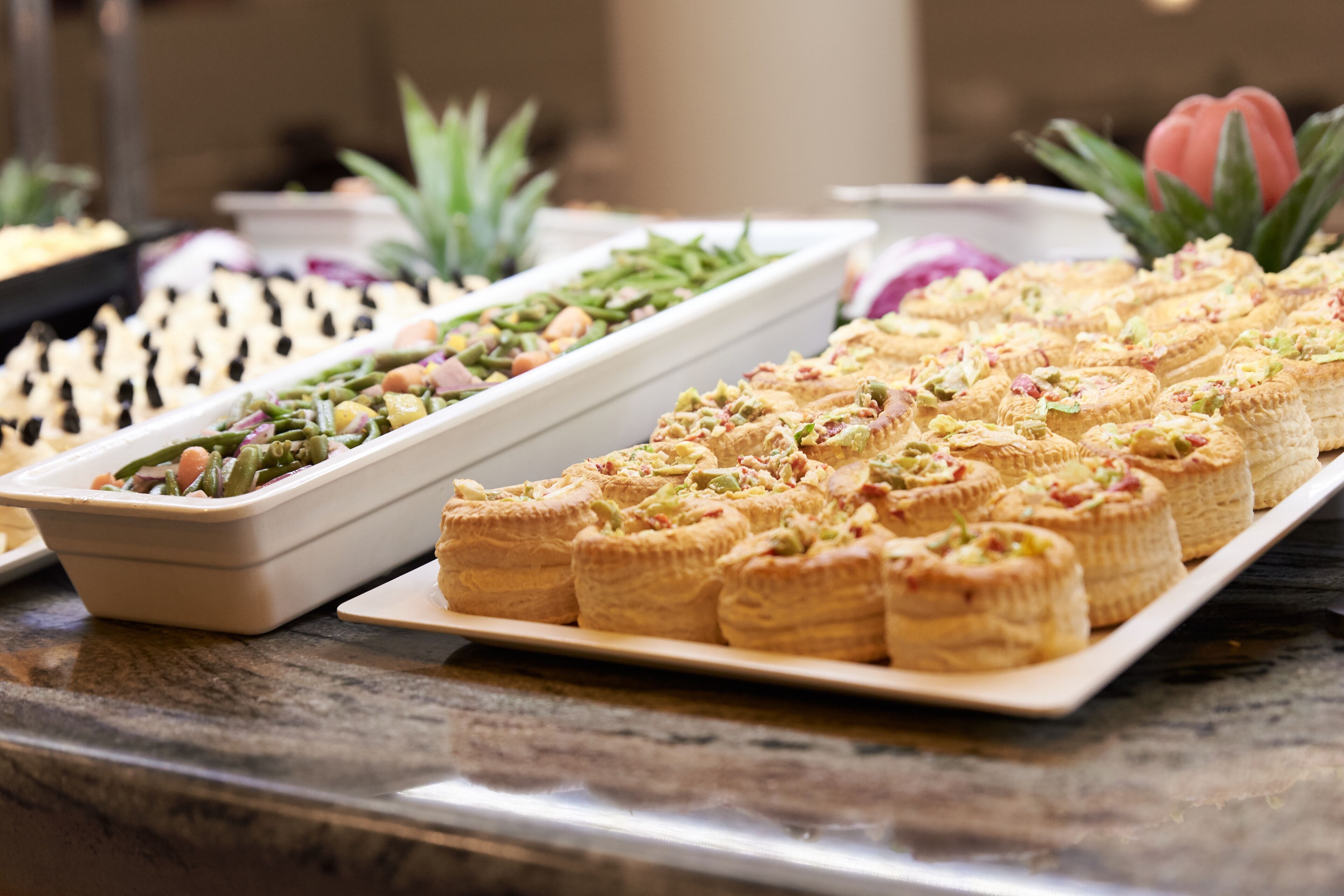 Un bufé con diversas opciones de comida, incluyendo pasteles y ensaladas.