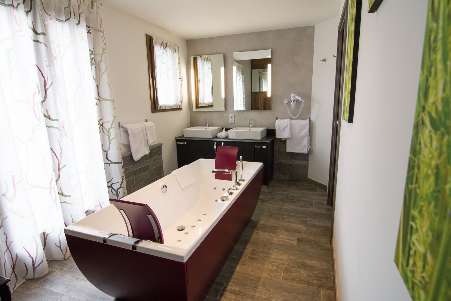 Een moderne badkamer met een ruime badkuip, twee wastafels en een spiegel.
