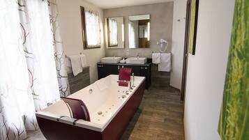 Een moderne badkamer met een ruime badkuip, twee wastafels en een spiegel.