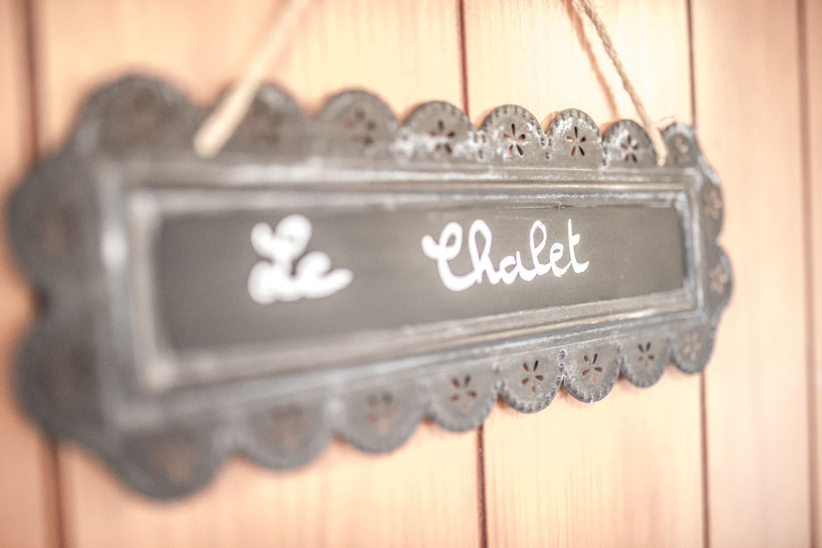 A decorative sign with the text "Le Chalet" in a rustic, carved frame.