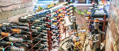Une cave à vin contenant de nombreuses bouteilles de vin rangées sur des étagères, avec une barrique placée au centre.