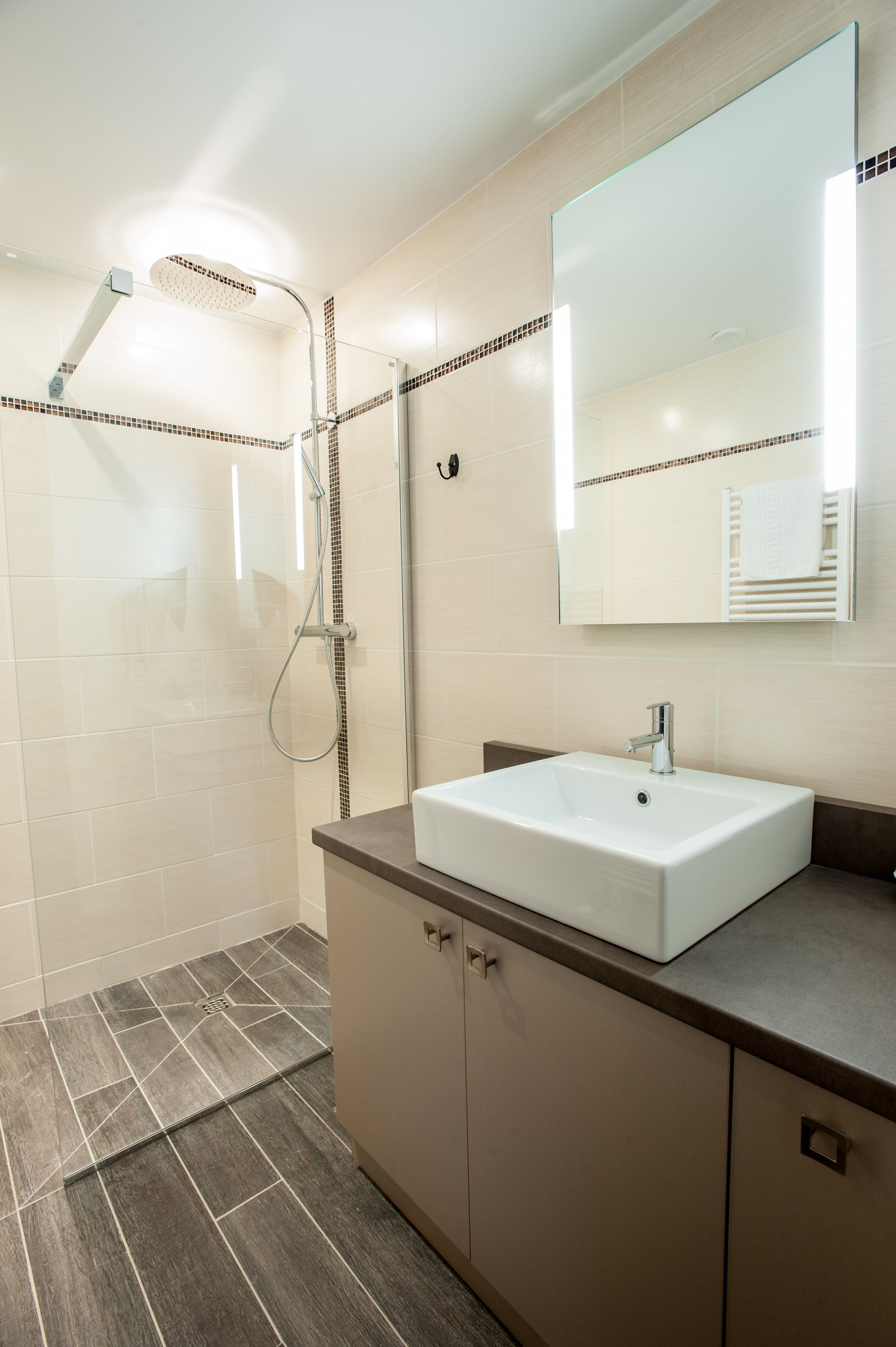Un baño moderno con ducha, lavamanos y un espejo grande.