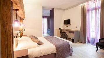 Una habitación de hotel con cama, escritorio, silla y televisor.