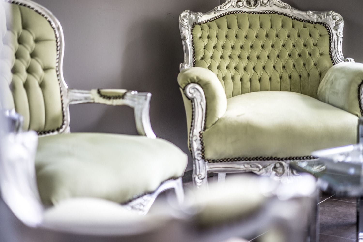 Dos sillones ornamentados con respaldo alto y tapicería capitonada.