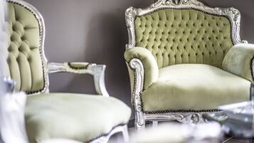 Dos sillones ornamentados con respaldo alto y tapicería capitonada.