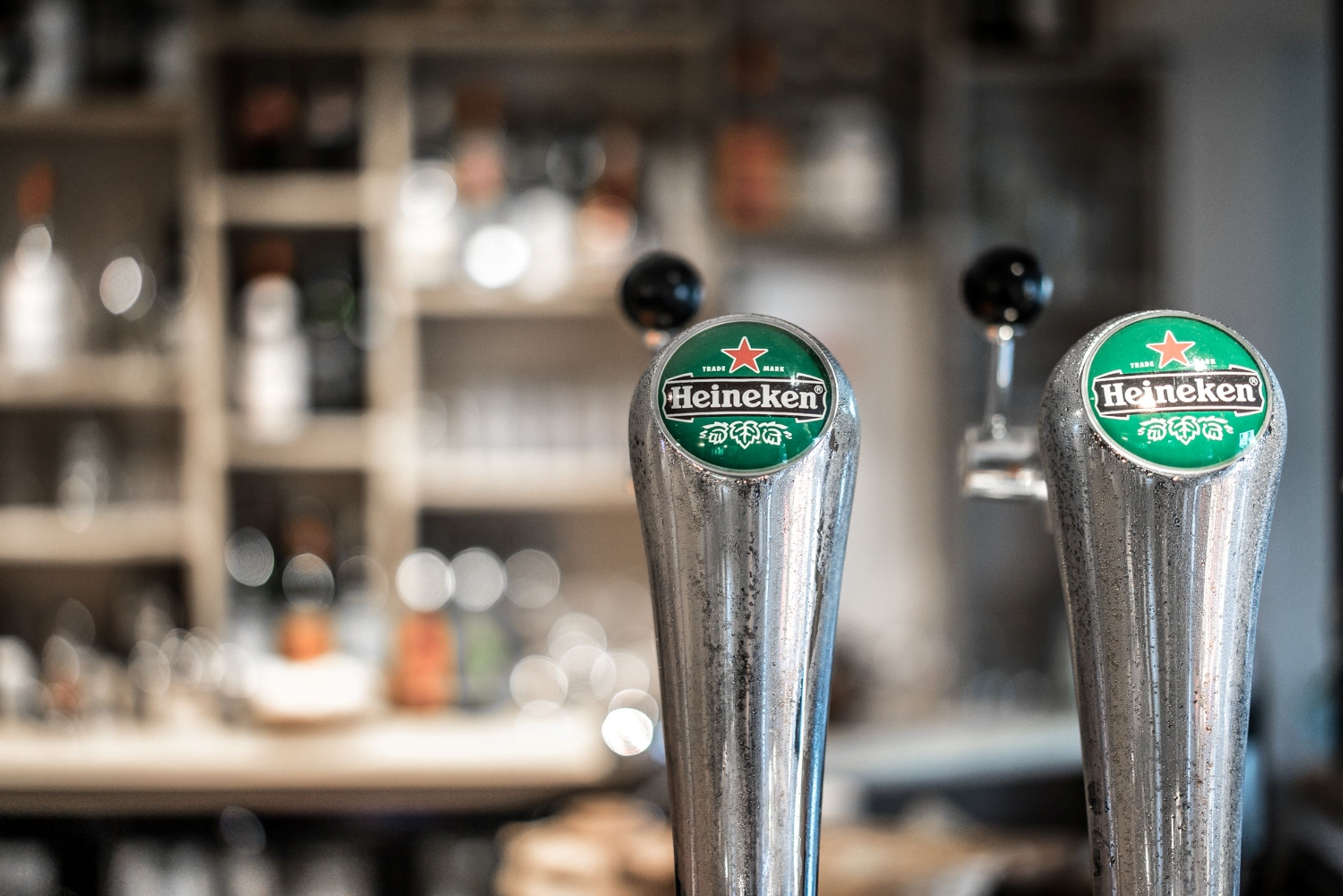 Two Heineken beer taps in a bar setting.