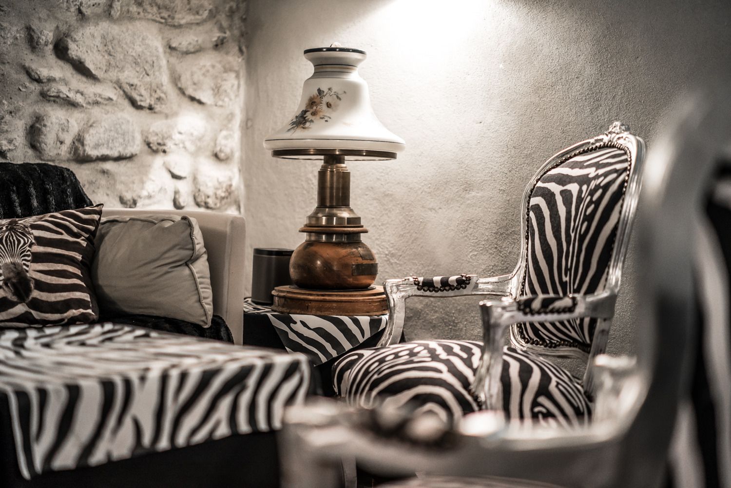 A room with a zebra-patterned bed, a lamp, and a chair with a similar pattern.