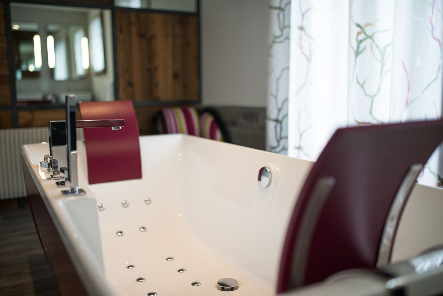 A modern bathroom with a freestanding bathtub, a mirror, and a wooden backdrop.
