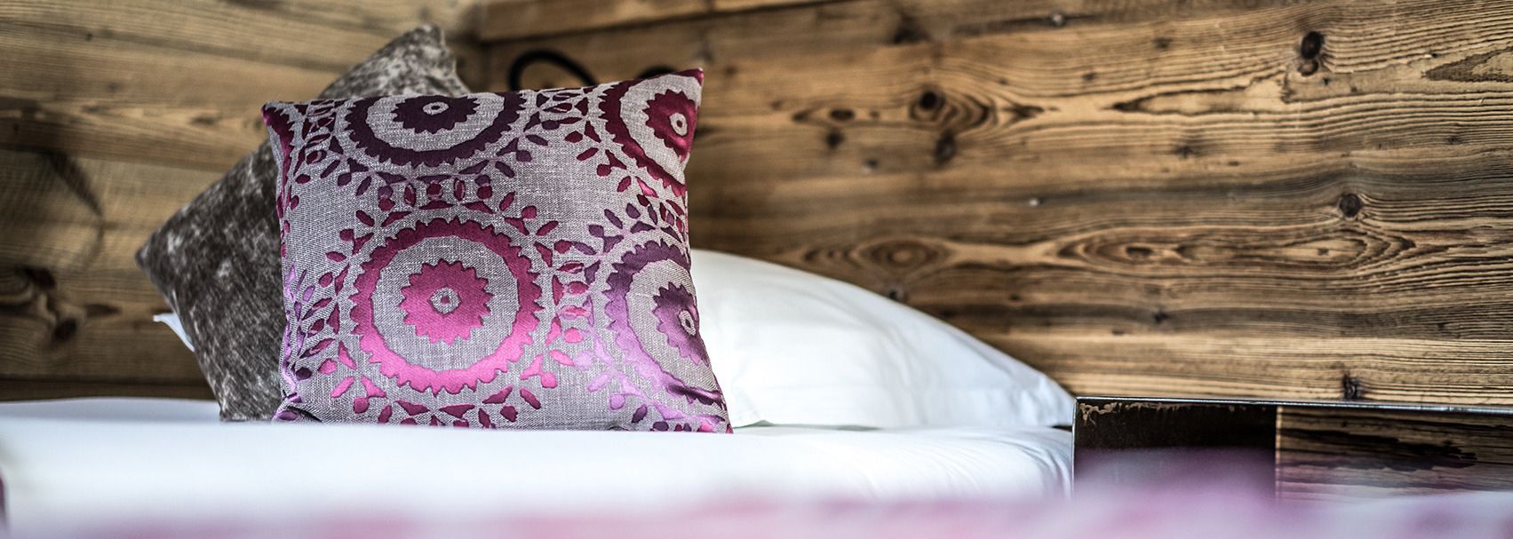 Un lit avec un oreiller blanc et un coussin décoratif à motifs floraux.