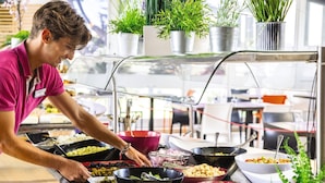 A buffet setup with various food items and a person serving.