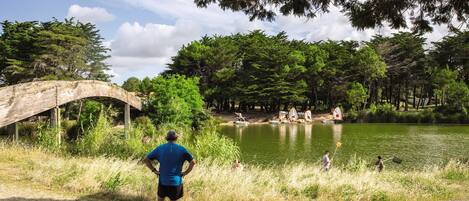 A wooden bridge over a lake with people fishing and a clear sky.