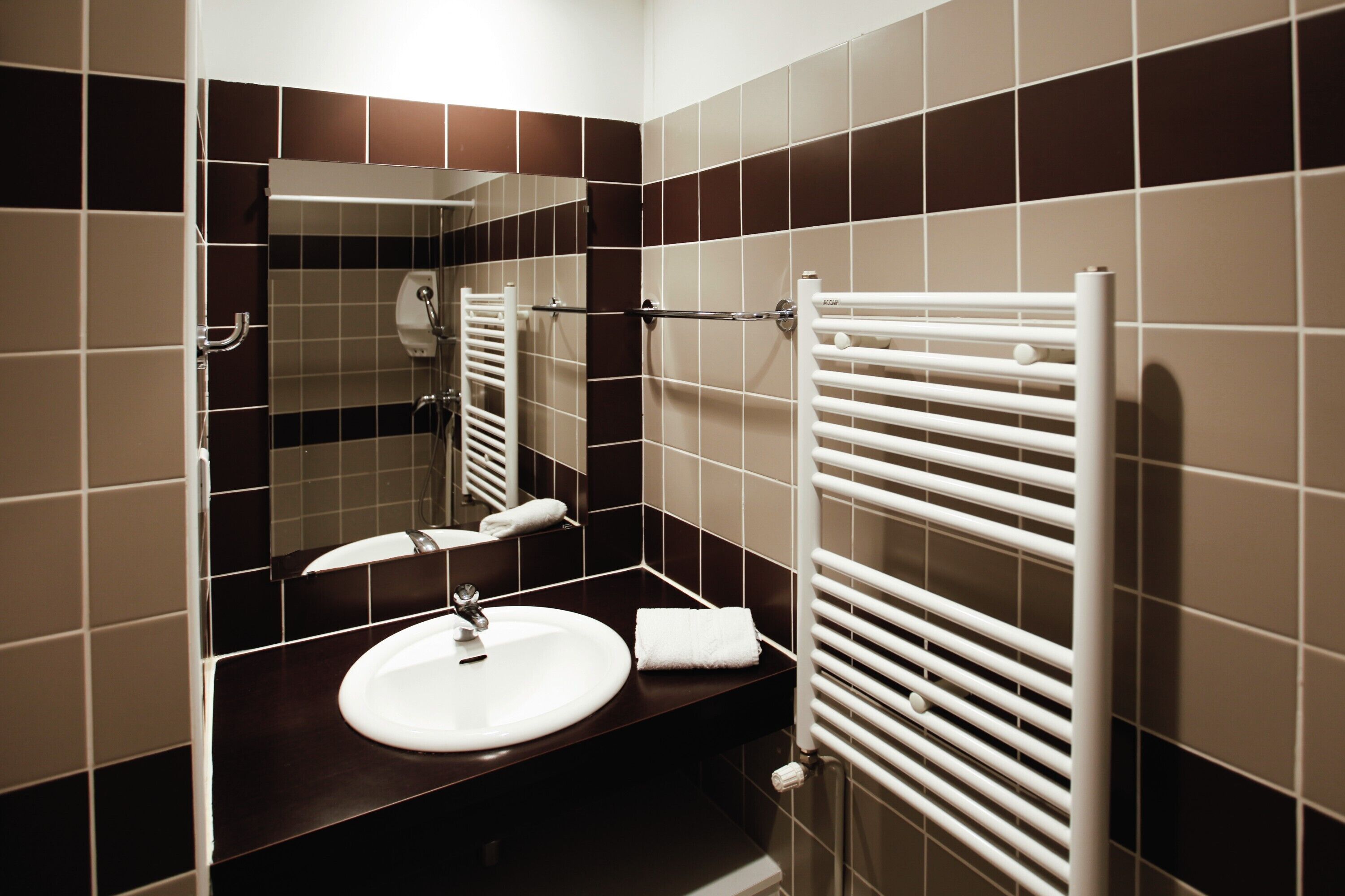 A modern bathroom with a white sink, a towel rack, and a mirror.