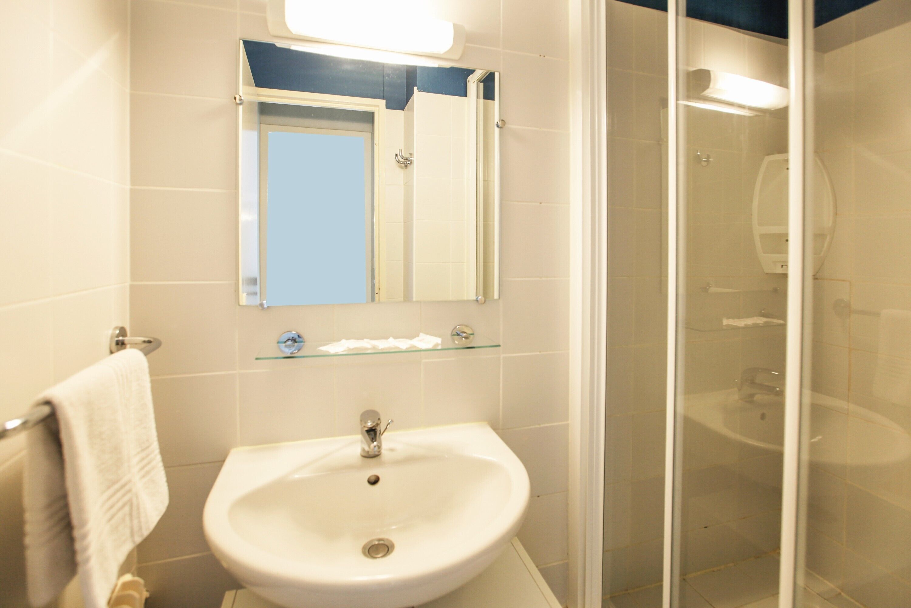 A bathroom with a white sink, a glass shower enclosure, and a mirror above the sink.