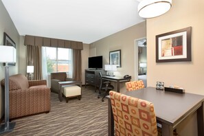 A hotel room with a sofa, a desk, a computer, a TV, and a dining table. - Homewood Suites by Hilton Henderson South Las Vegas (Henderson)