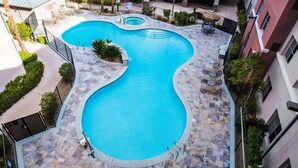 Una piscina de borde ondulado, rodeada por un patio de piedra y mobiliario exterior.