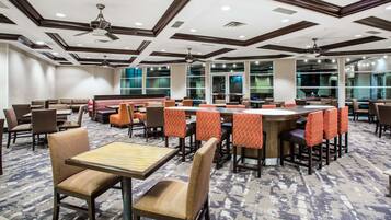 A hotel lobby with multiple seating areas, including booths and tables, and large windows providing views.