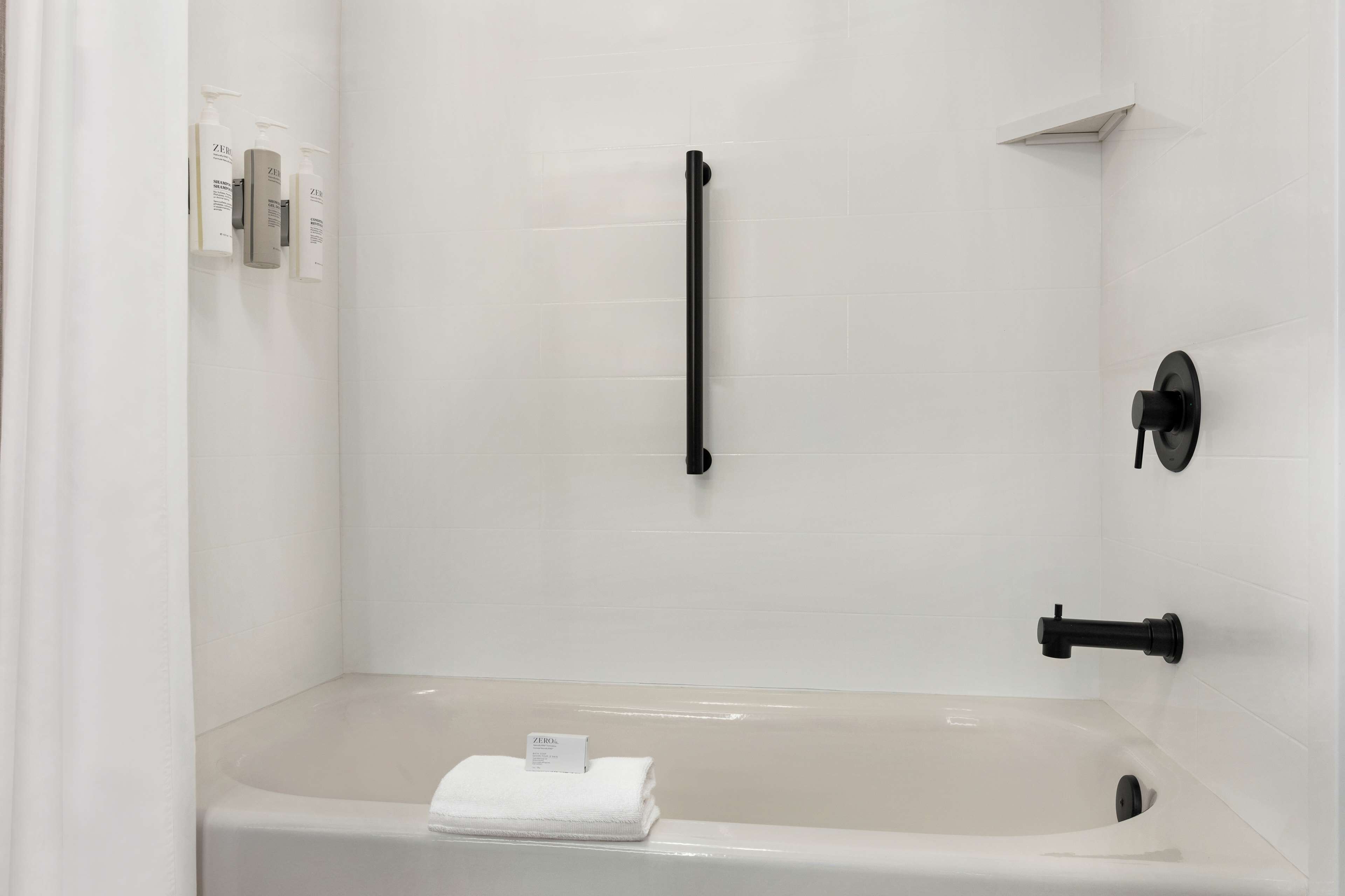 Un baño moderno con bañera, perchero y secamanos.