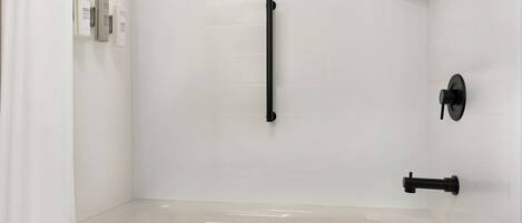 Une salle de bain moderne équipée d’une baignoire, d’un porte-serviettes et d’un sèche-mains.
