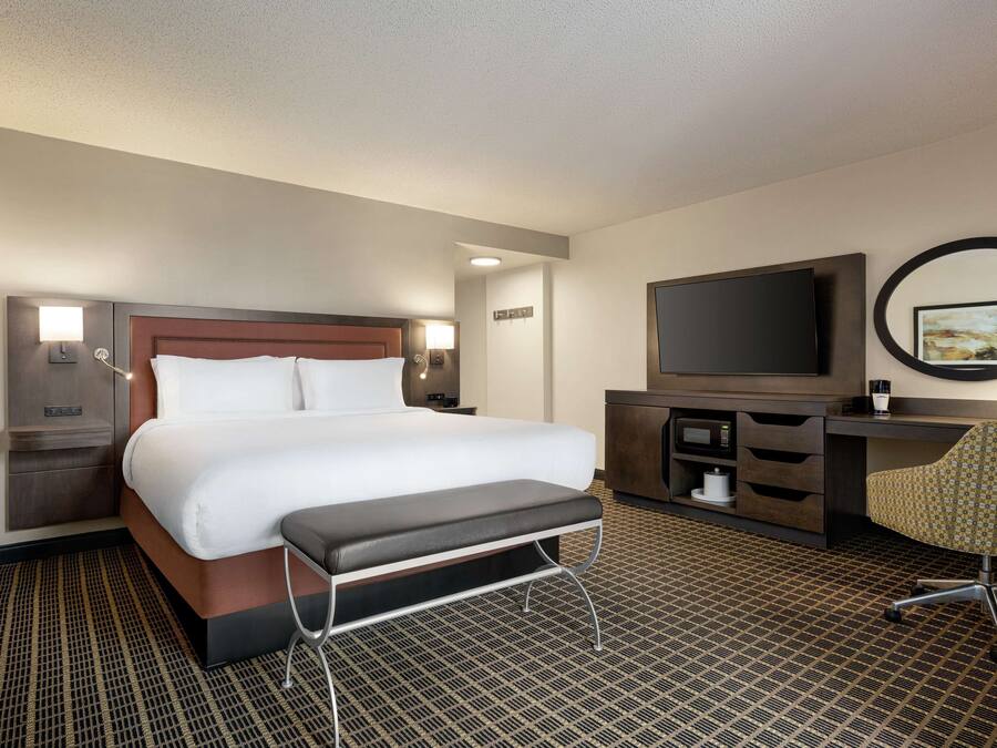 Une chambre d’hôtel avec un grand lit, un bureau avec une chaise, une télévision et un miroir.