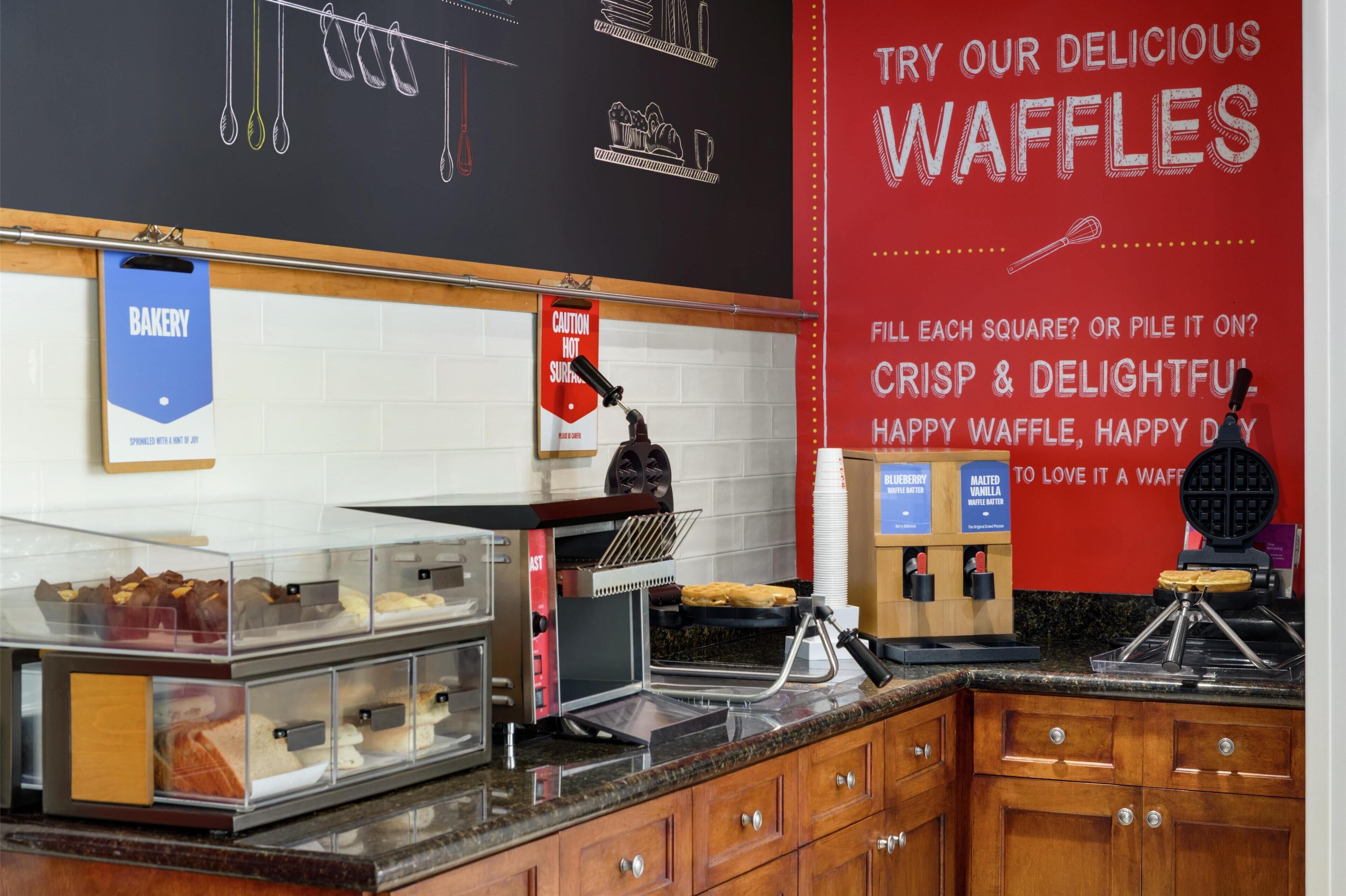 A bakery section with waffle makers and a sign advertising delicious waffles.